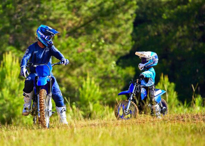 Adult riding a Yamaha dirt bike with child riding a Yamaha pw50